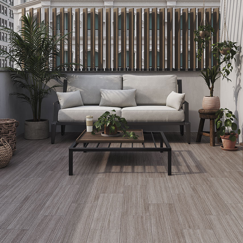 Terraza moderna con piso tipo madera, sofá gris y plantas decorativas