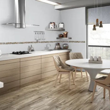 Cocina moderna con pisos tipo madera, muebles beige y mesa redonda junto a ventana grande.